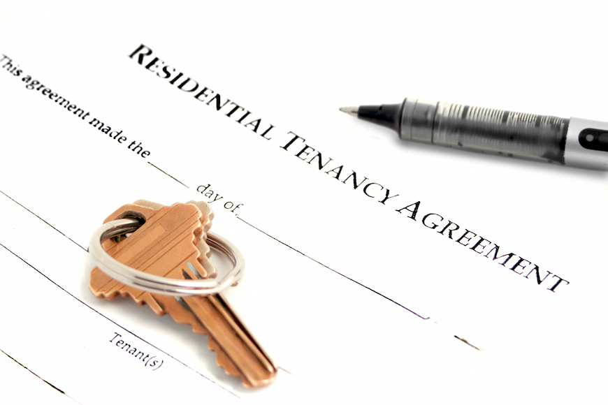 A close up image of tenancy agreement, along with the keys to a rental property.