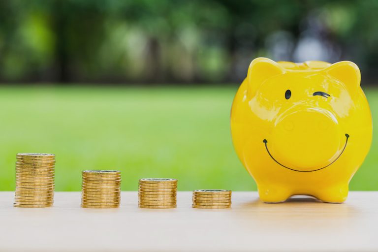 smiling piggy bank next to a pile of coins