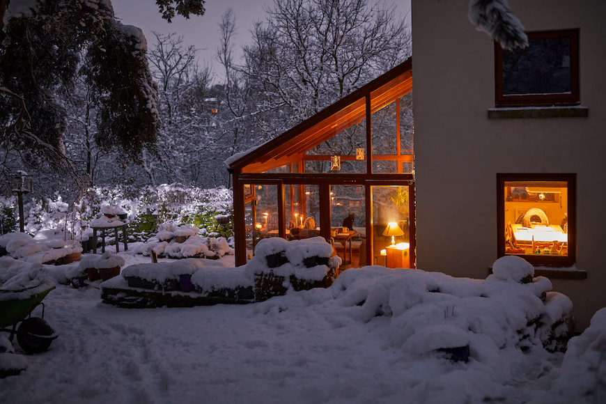 picture of home with lights on from outside in the snow