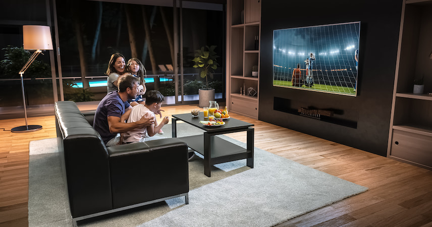 Family watching a football match together on the tv while sitting on the couch