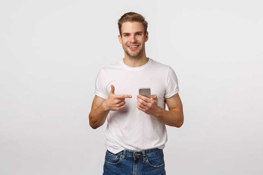 Man pointing at his phone and smiling in front of a white background