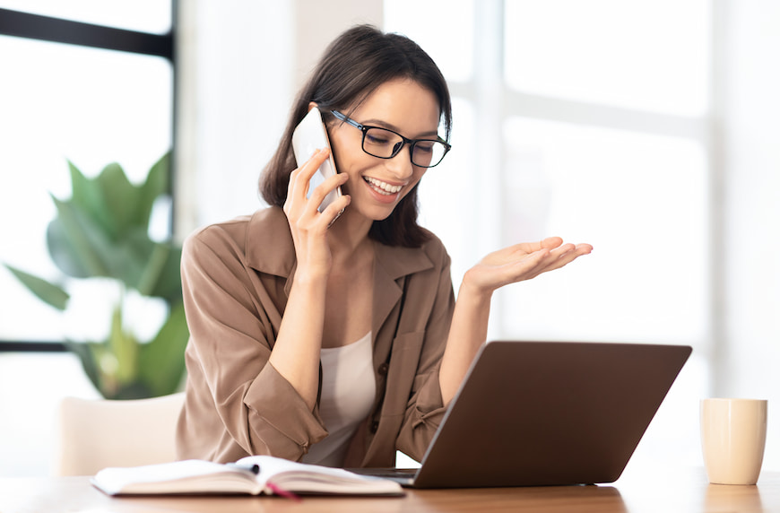 Women talking on cell phone while working on her laptop