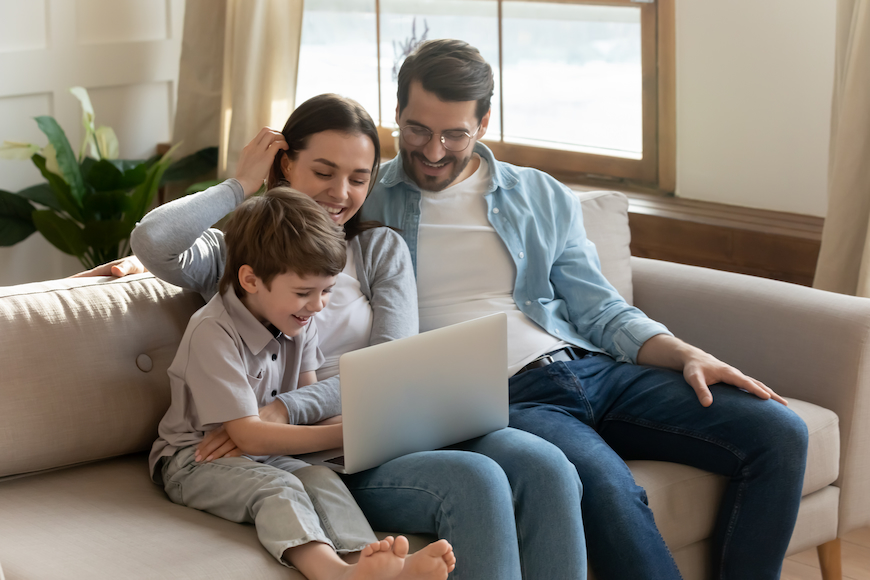 A father, mother, and a young boy all looking at the same computer screen.