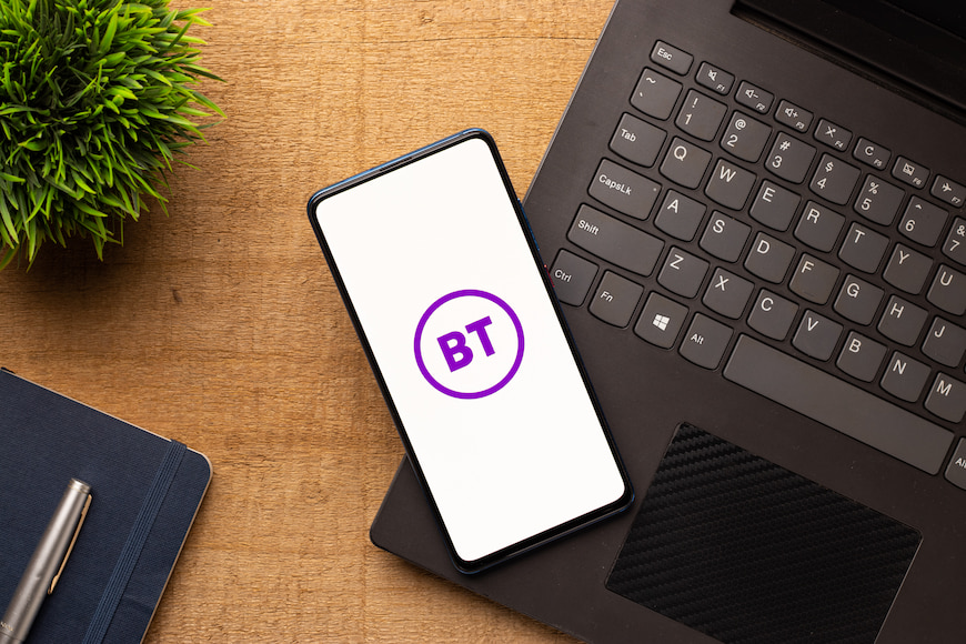 Smart phone with a BT Logo on it resting on a table.