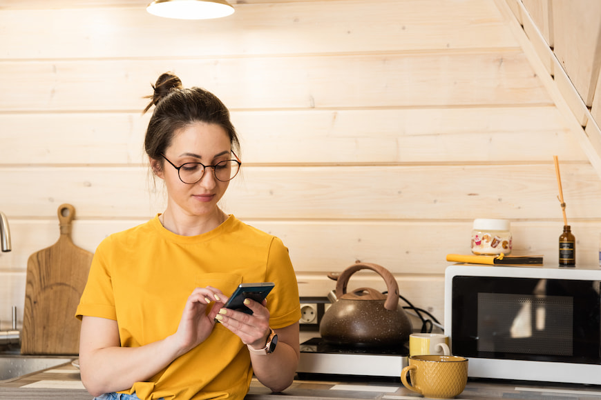 Woman using her phone inside her kitchen