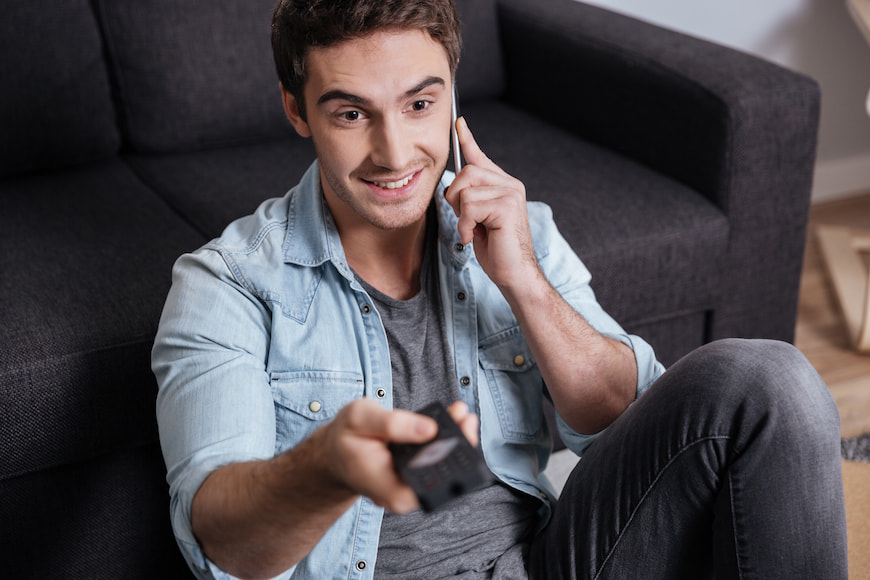 Man on the phone while watching TV and using the remote