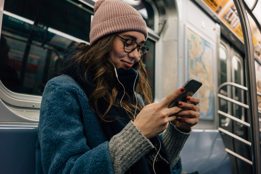 Woman listening to music and using her phone while she is on the train