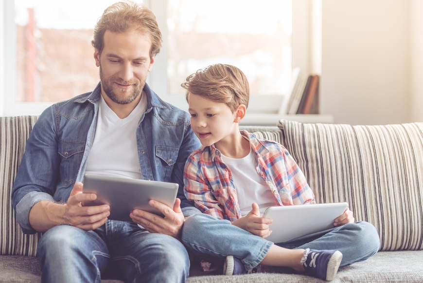 Father and son sitting on the couch enjoying ultra fast broadbanddeals