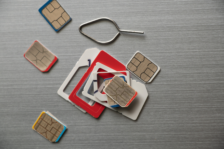 Multiple SIM cards and a pin on a surface